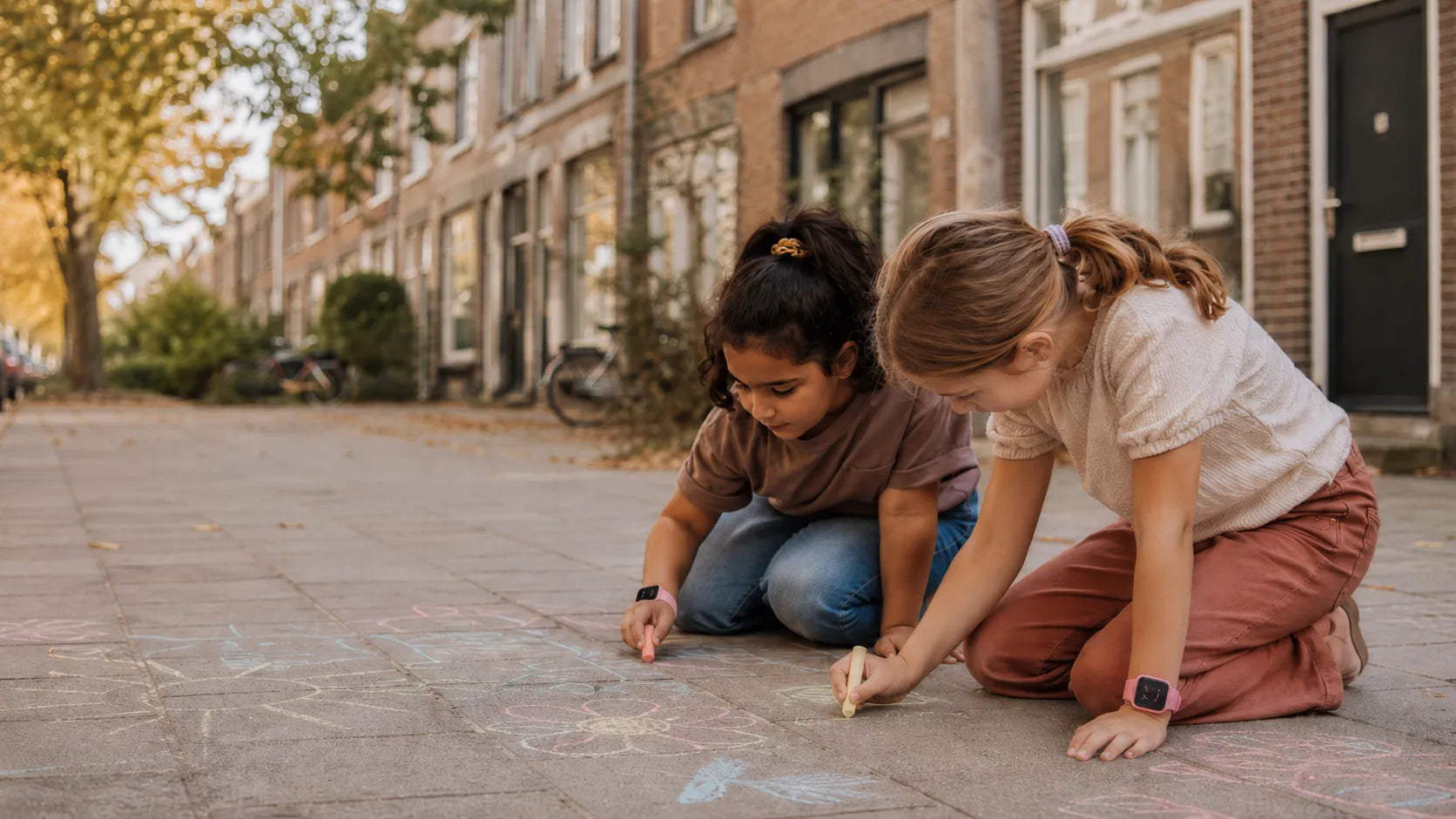 Twee kinderen die aan het stoepkrijten zijn met het GPS horloge kind om